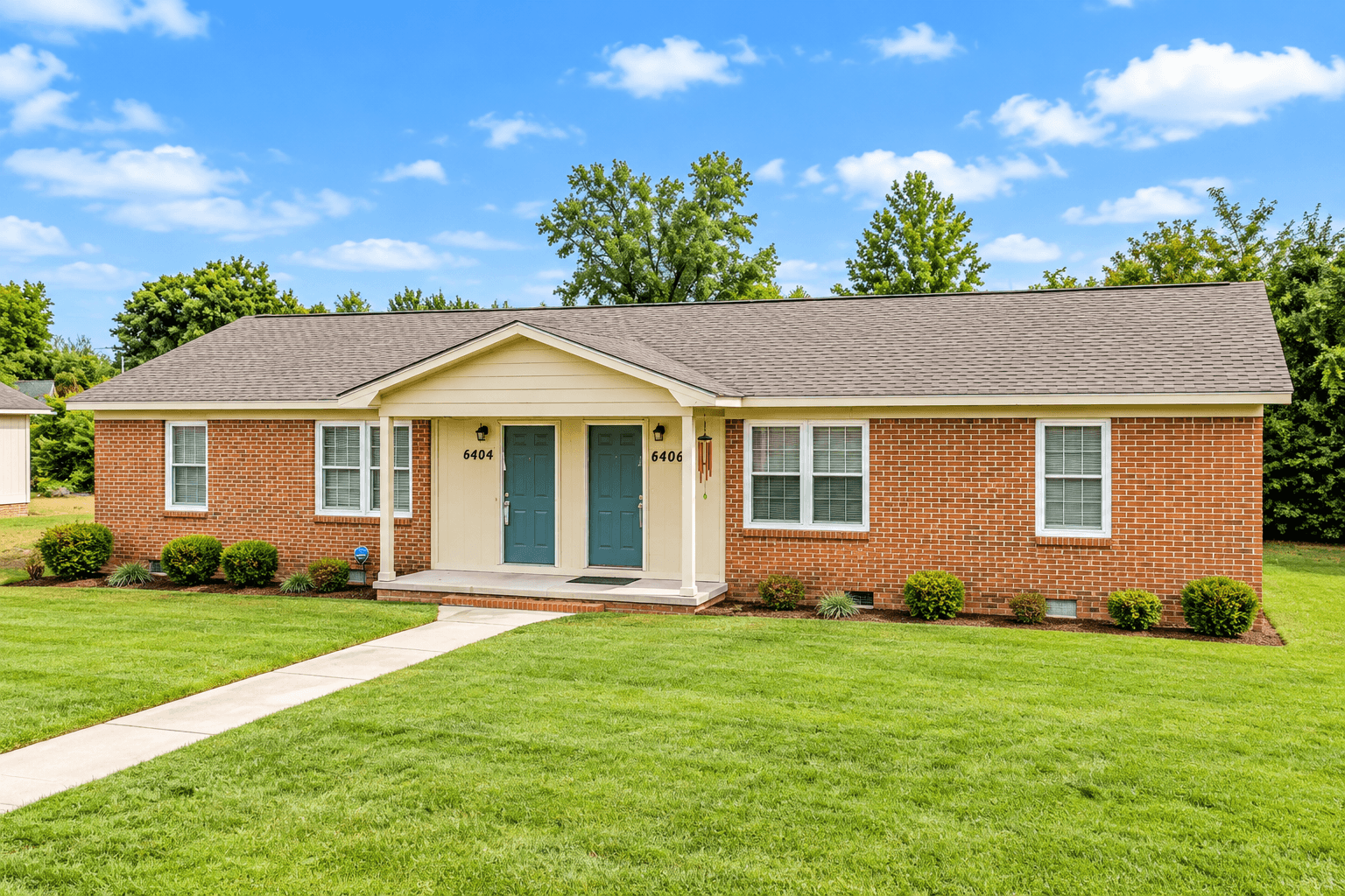 A red brick house with a green door and a small porch.